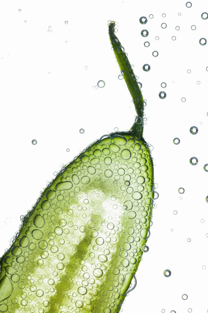 Close-up of air bubbles covering piece of fresh cucumber floatin